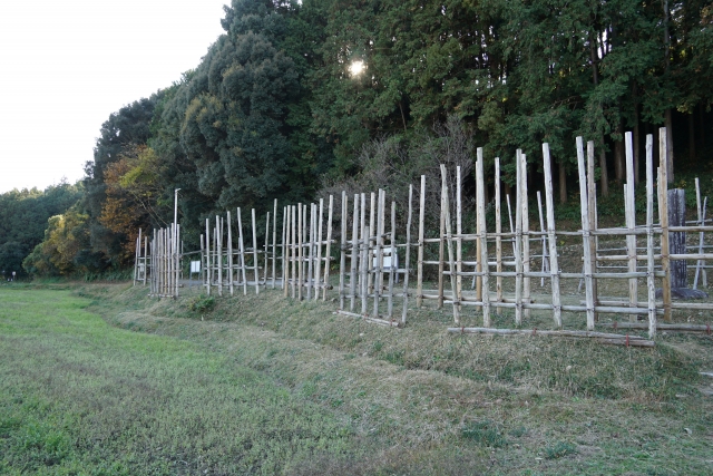 長篠の戦いの古戦場に復元された馬防柵を見ながら馬場信房の名言を回想しているイメージ写真